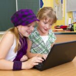 Kaksi tyttöä tekee ohjelmointiprojektia koululuokassa.