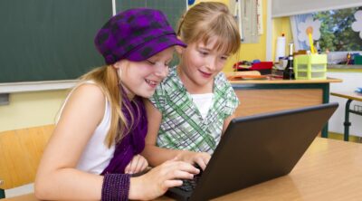 Kaksi tyttöä tekee ohjelmointiprojektia koululuokassa.